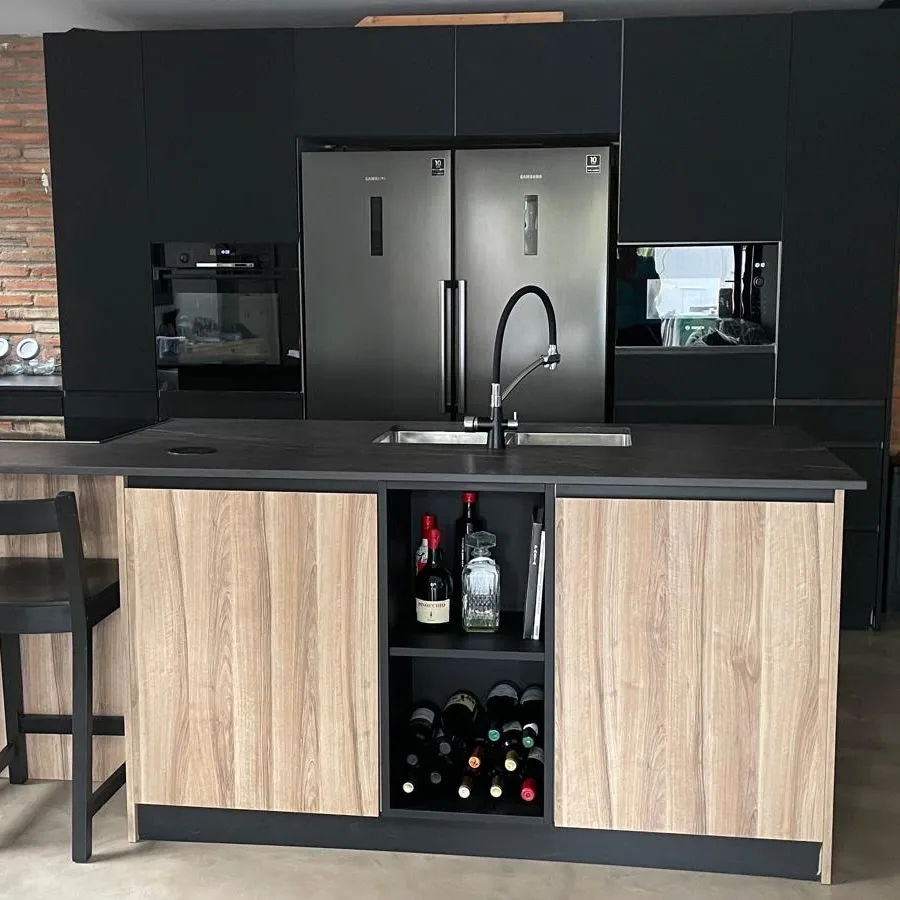 Cocina reformada con isla central, frentes de madera y mobiliario negro