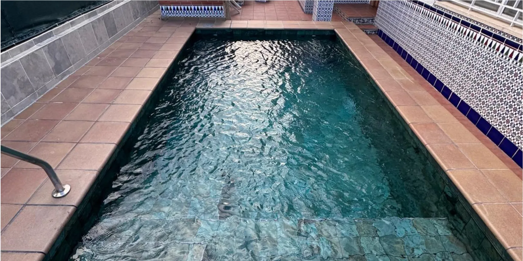 Piscina terminada y llena de agua, con coronación de gres